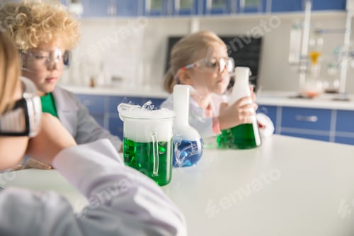 Preview: Kids in protective glasses and lab coats making experiment in chemical laboratory