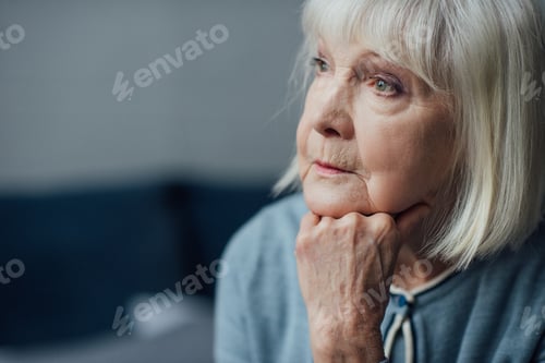 Preview: portrait of thoughtful senior woman propping chin with hand at home