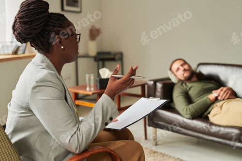 Preview: African American psychologist talking to patient at office