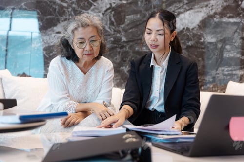Preview: Senior woman and young businesswoman reviewing and discussing documents together