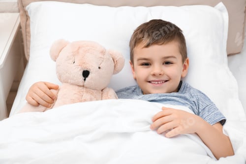 Preview: Cute child with teddy bear resting in bed at hospital