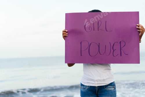 Preview: Woman at the beach holding girl power sign promoting feminism and women empowerment