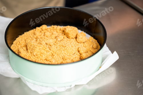 Preview: Pastry chef preparing crumble base for dessert in round baking pan