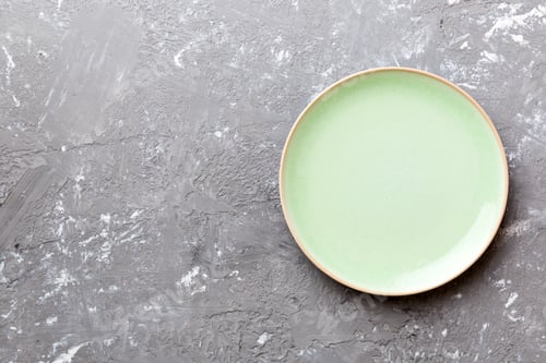 Preview: Top view of empty green plate on cement background. Empty space for your design