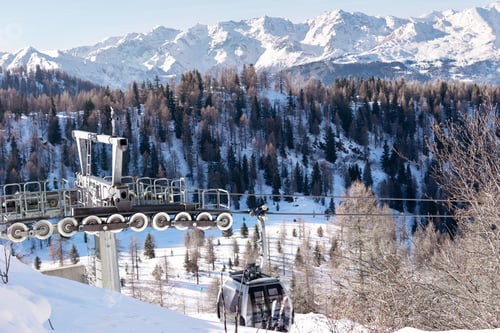 Preview: The metal structure of the cableway against the backdrop of snow-capped mountains of the Dolomites