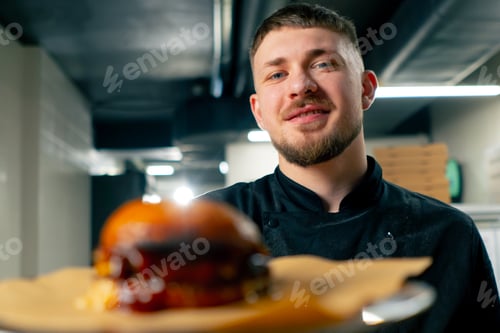 Preview: close-up in professional kitchen the chef stands with a prepared burger in a plate