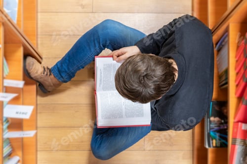 Preview: top view of student lay on wooden floor and read a book b