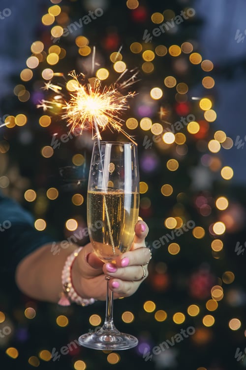 Preview: Champagne in hand against the background of the Christmas tree. Selective focus.