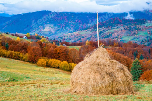Preview: Sunrise in misty morning valley with haystack on grassland hill