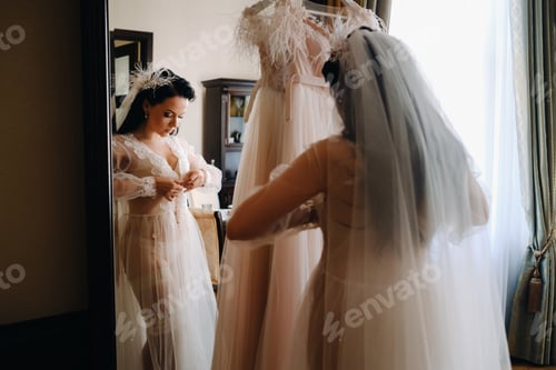 Preview: the bride, dressed in a boudoir transparent dress and underwear, stands at home in the morning by