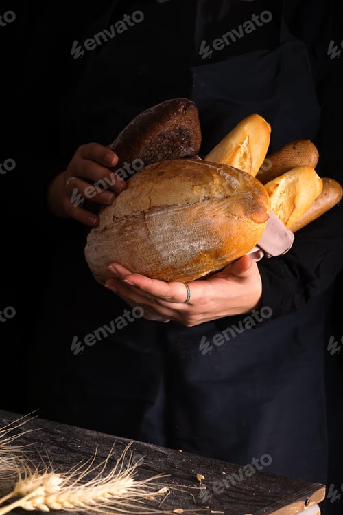 Preview: Woman holding tasty fresh bread sorts on a dark