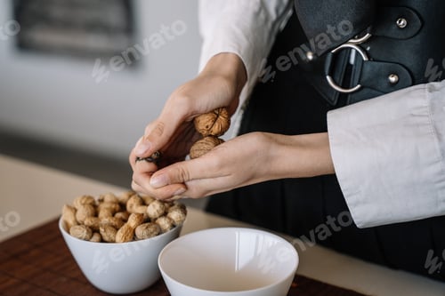 Preview: close-up view of a person cracking two walnuts with her hands