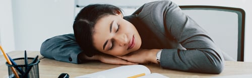 Preview: panoramic shot of tired latin businesswoman sleeping at workplace in office