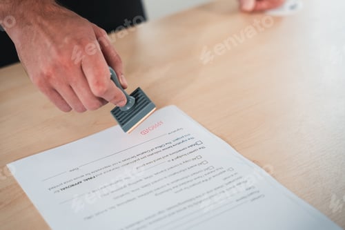 Preview: Businessman hand stamping an approved stamp on a text document.
