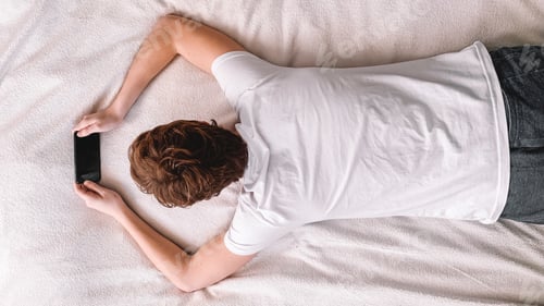Preview: The man is lying on the bed and looking at the phone