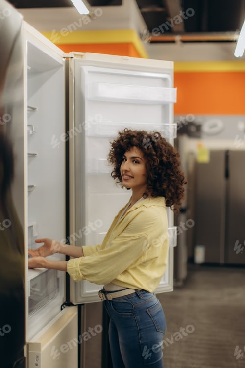 Preview: Young Woman Examining a Refrigerator in an Electronics Store