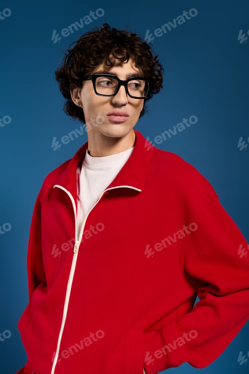 Preview: Young stylish man exudes confidence in vibrant red attire against a blue background