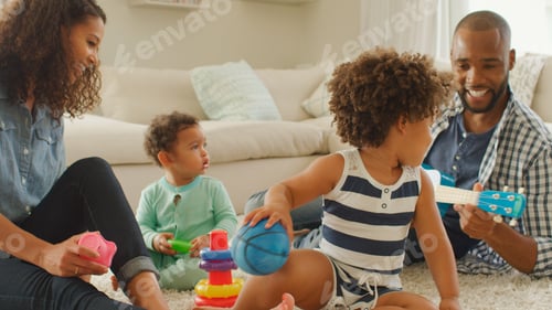 Preview: Parents Sitting With Children At Home Playing With Guitar Or Ukulele And Plastic Toys