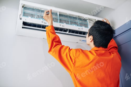 Adult Repairing Air Conditioner in Bright Orange Shirt