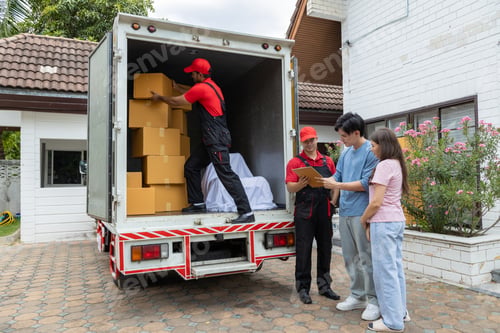 Preview: Young couple checks with two movers unloading boxes and furniture from a pickup truck
