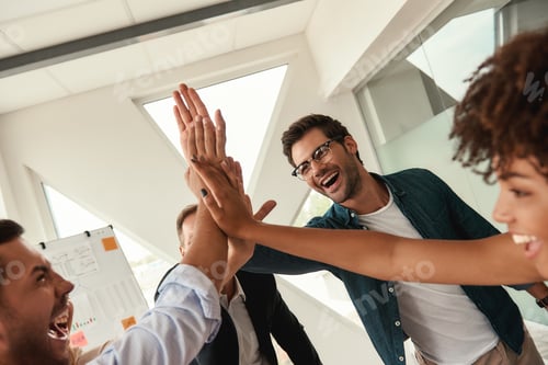 Preview: Our success Business people giving each other high-five and smiling while working together in the