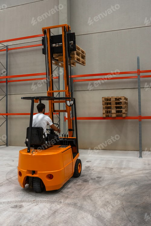 Preview: Vertical shot of a male operating an industrial lifting machine in a warehouse