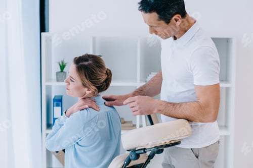 Preview: masseur looking at client with neckpain at office