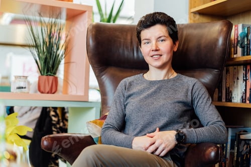 Preview: Confident, relaxed middle aged female expert sits in a leather armchair in cozy office