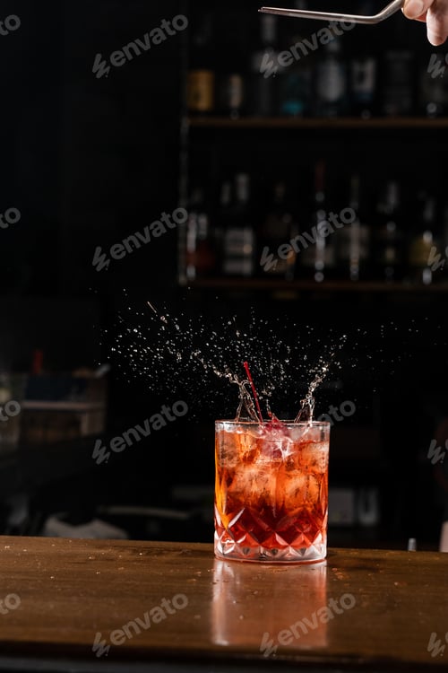 Preview: Cherry splashes into Negroni cocktail during garnish