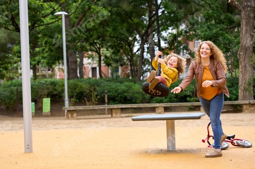 Preview: A mother is holding her daughter on a swing