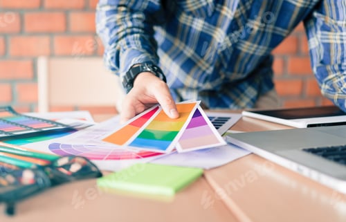 Preview: Designer choosing colors for doing graphic on laptop.