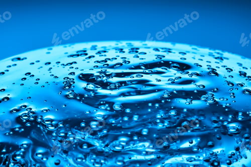 Preview: The viscous gel serum for the face flows and collects into a drop on a blue background..