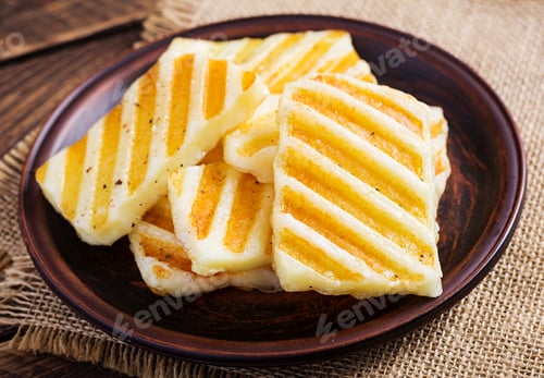 Preview: Traditional grilled halloumi cheese on plate on wooden background.