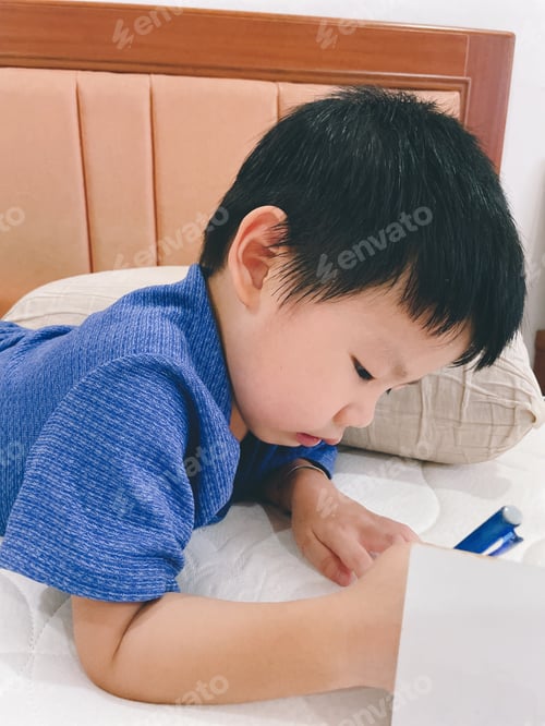 Preview: Child Lying on Bed in Blue Shirt