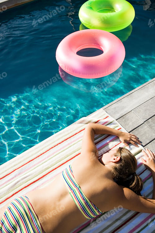 Preview: Young woman sunbathing at poolside