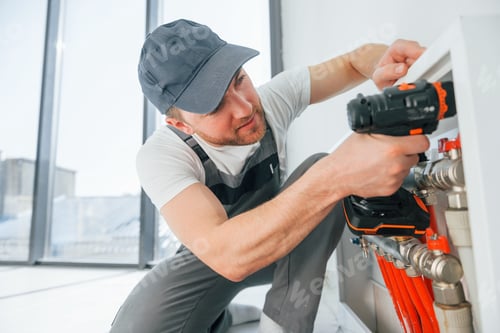 Preview: Installing pipes. Repairman is working indoors in the modern room