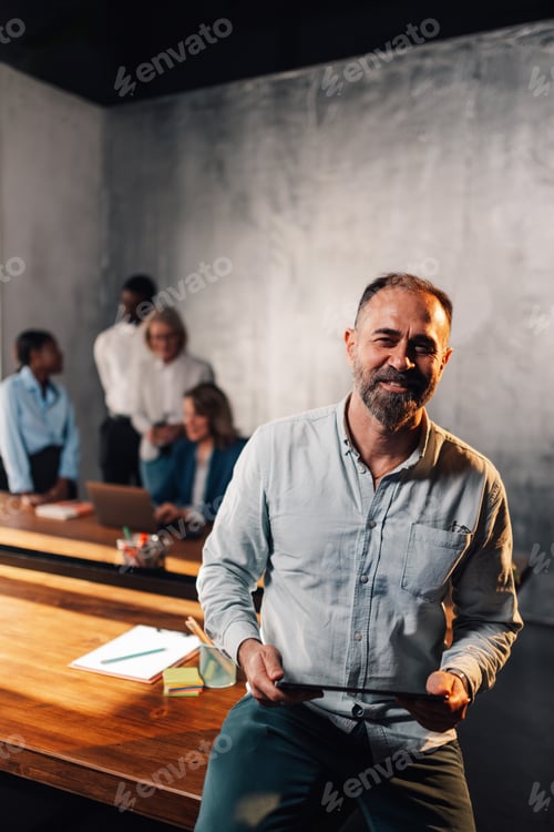 Preview: Smiling mature businesswoman using tablet at office during the meeting