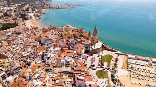 Preview: Aerial view of Sitges coastal village and Iglesia de San Bartolomé y Santa Tecla during a sunny day