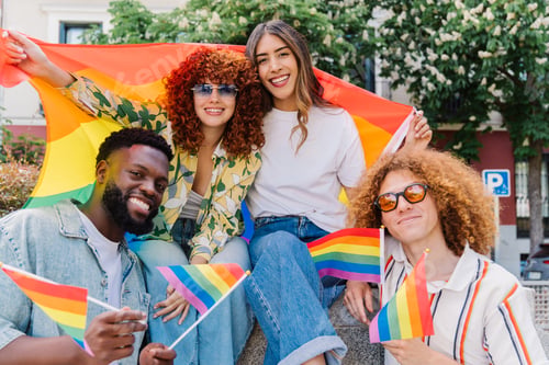 Preview: Happy friends waving rainbow flags, symbolizing pride and support for the LGBTQ+ community