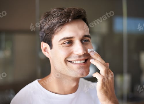Man Applying Cream to Face Smiling Indoors