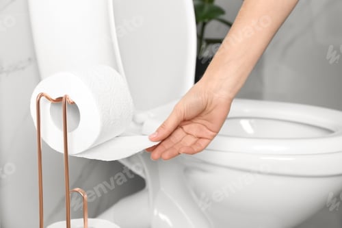 Preview: Woman taking toilet paper from roll holder in bathroom, closeup