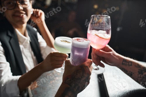 Preview: happy african american woman clinking glasses with tattooed men while resting in bar after work