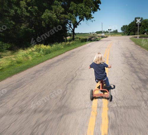 Preview: Rear view of boy riding bicycle on road