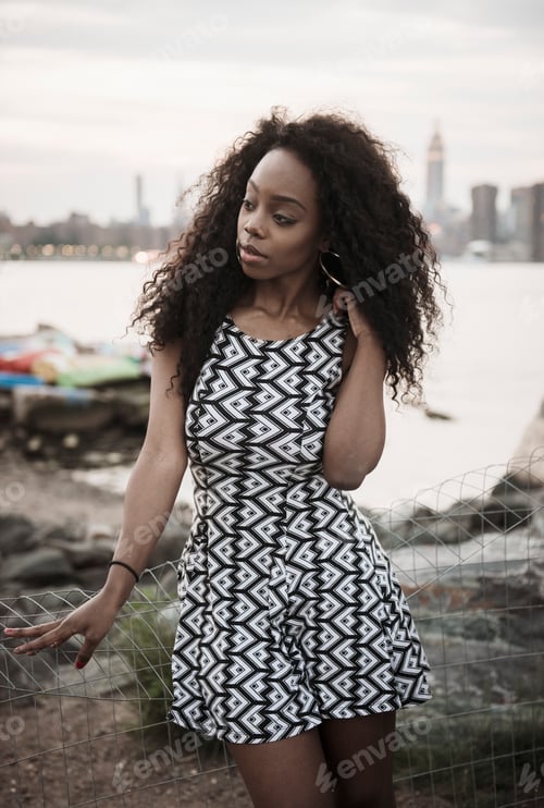 Preview: Young woman posing by the waterfront with city skyline in the background
