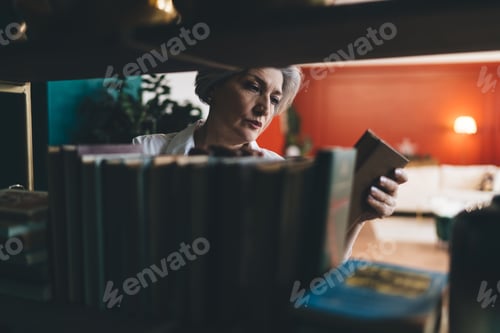 Preview: Curious mature woman reading book cover in library