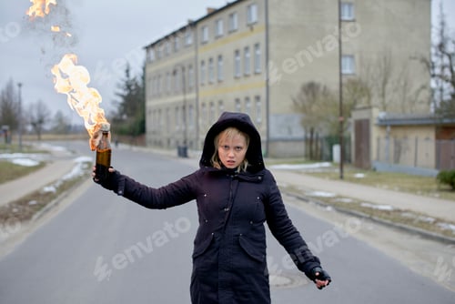 Preview: Woman holding a flaming bottle in an urban street