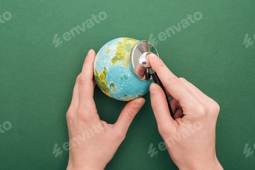 Preview: cropped view of woman holding toy earth and stethoscope on green background