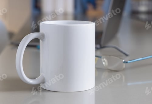 Preview: White coffee mug on grey office table against opened laptop and glasses closeup, mockup