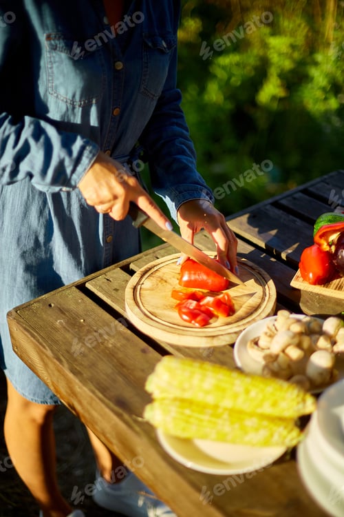 Preview: Unrecognizable woman cutting fresh pepper vegetables on wooden board