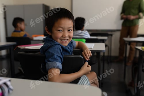 Preview: Happy schoolboy looking back in classroom